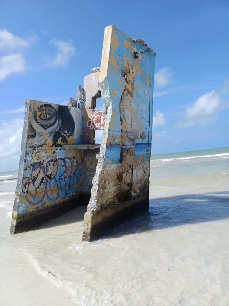 Pared de una casa antigua en la playa de Holbox pintada con un mural colorido y artístico