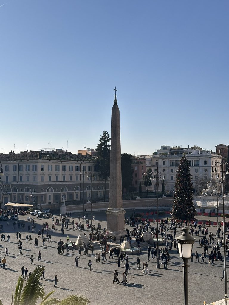 Piazza del Popolo, Roma. Vista de la plaza con obelisco central e iglesias barrocas. Espacio público con gente.