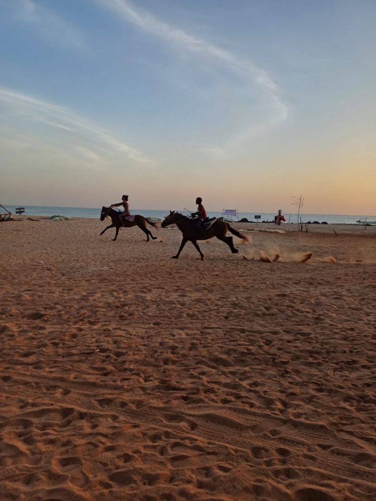 Jóvenes cabalgando a lo largo de la playa de Saly, Senegal