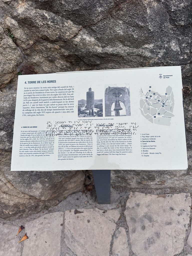 Cartel explicativo junto a la Torre de las Horas en Pals, con información sobre su origen románico y su historia medieval.