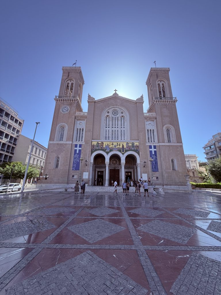 Fachada de la Catedral Metropolitana de Atenas desde la Plaza Mitropoleos, con detalles arquitectónicos neobizantinos y ambiente urbano