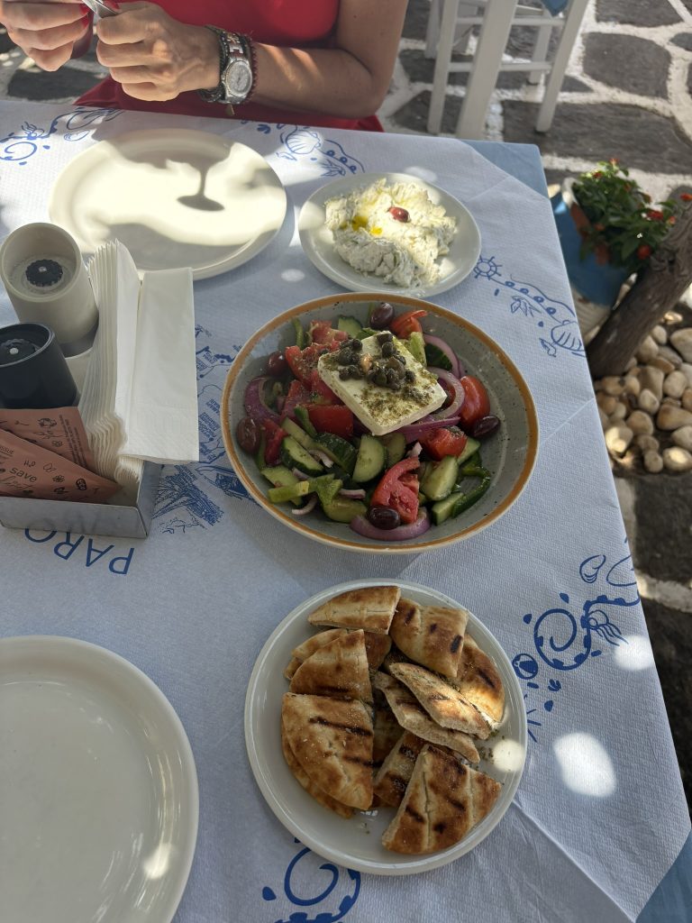 Mesa con platos típicos de la cocina griega: souvlaki, ensalada con feta, pita y yogur con miel