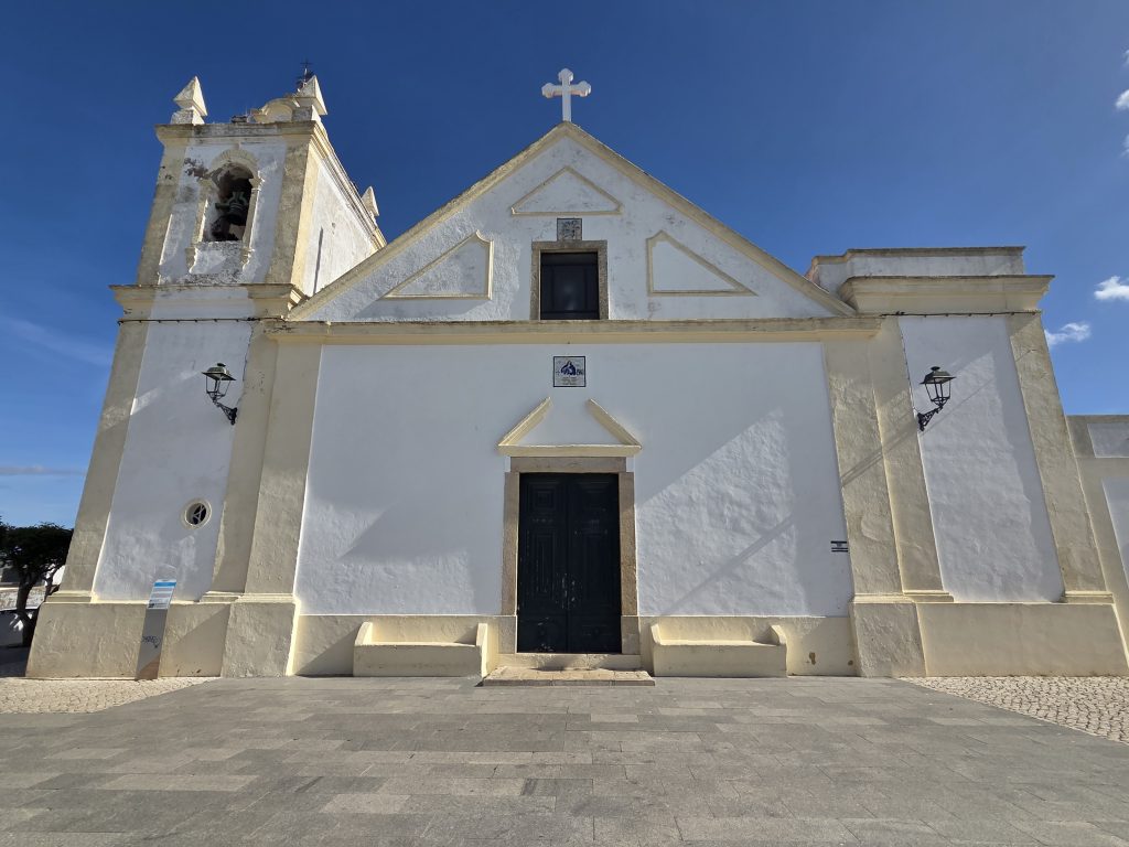 Fachada principal de la Iglesia de Nossa Senhora da Conceição en Ferragudo, Algarve, con cielo despejado y arquitectura tradicional portuguesa