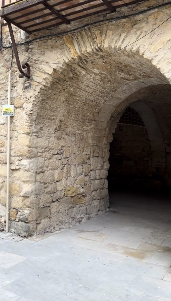 Arco de piedra ancho en una de las plazas principales de Peratallada, que muestra la arquitectura medieval típica del pueblo