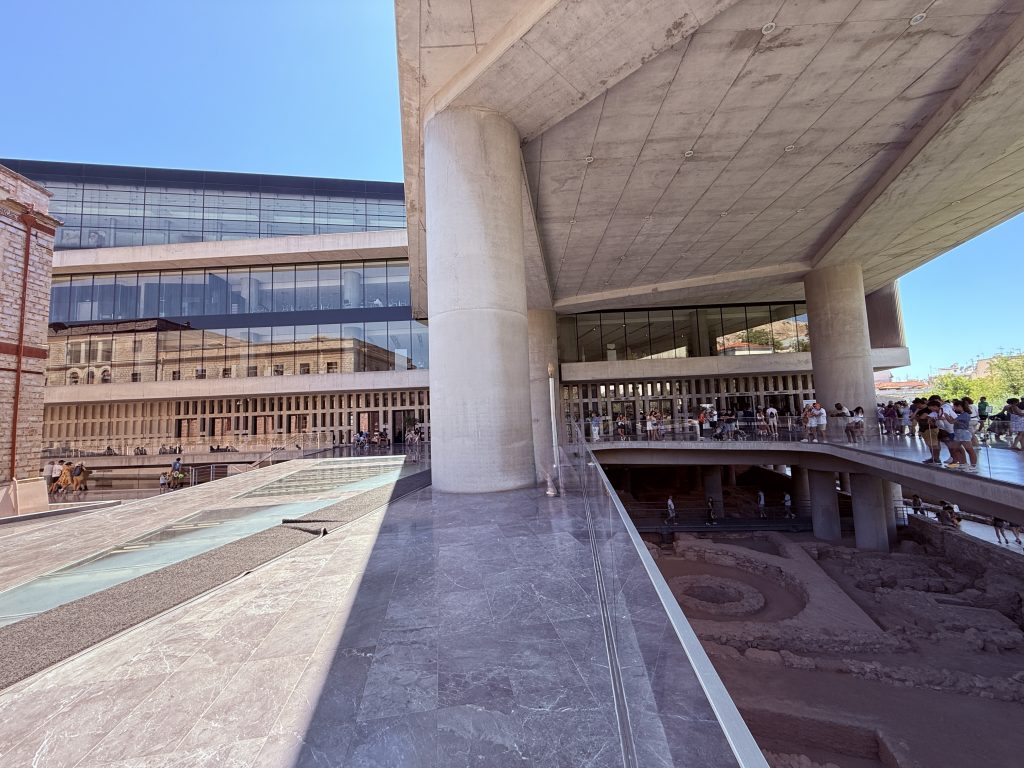 Fachada moderna del Museo de la Acrópolis en Atenas, con arquitectura contemporánea junto a las ruinas históricas
