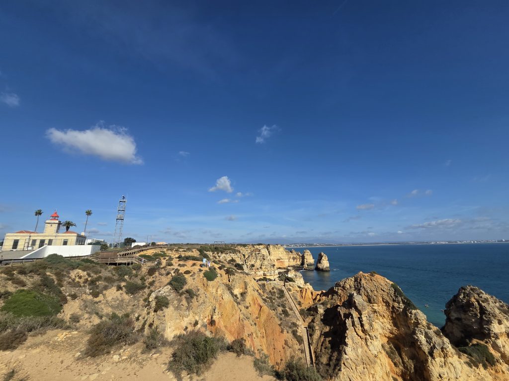 Vista panorámica de los acantilados y el faro de Ponta da Piedade, en Lagos, con pasarelas de madera y el océano Atlántico al fondo