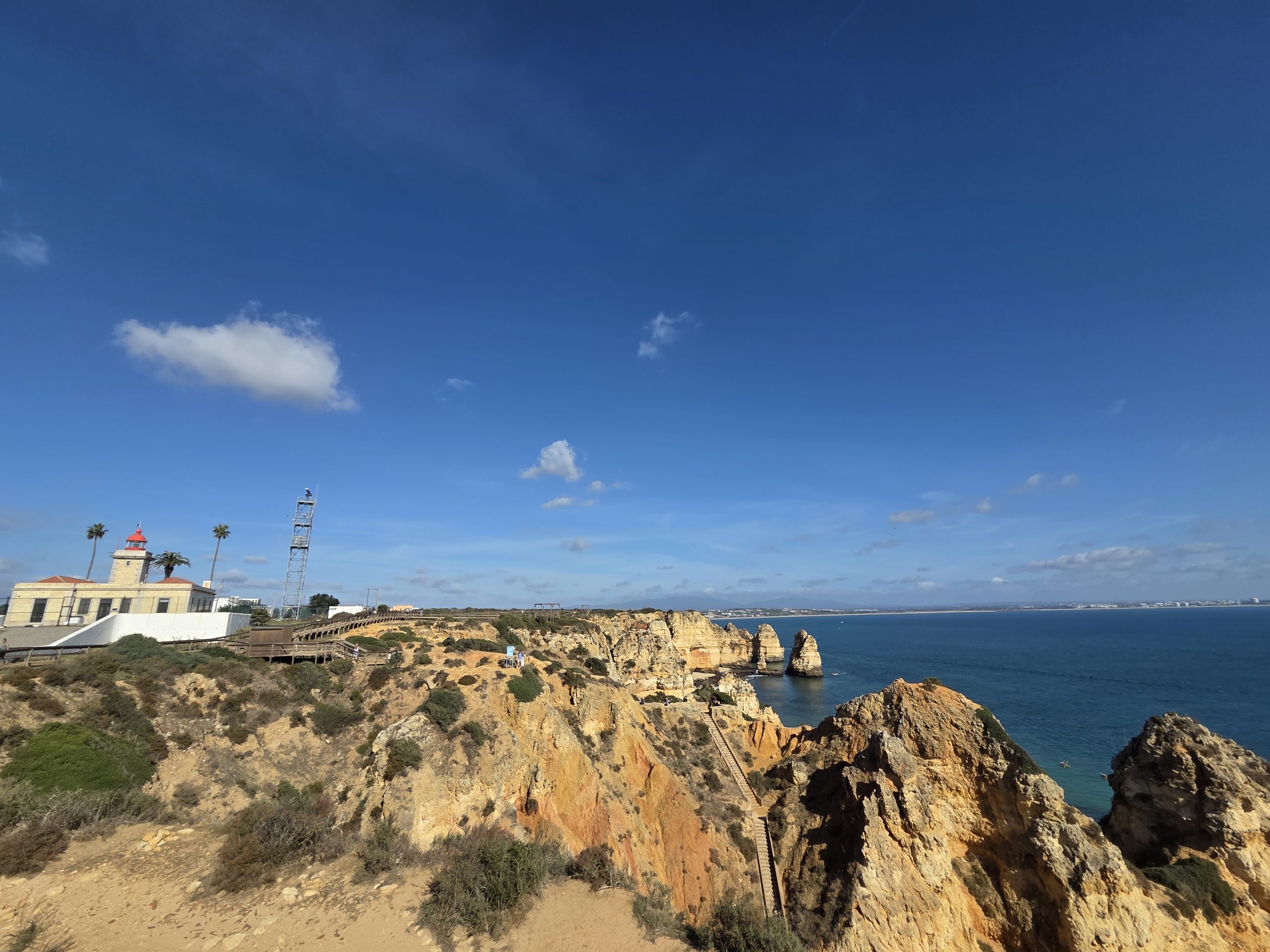 Vista panorámica de los acantilados y el faro de Ponta da Piedade, en Lagos, con pasarelas de madera y el océano Atlántico al fondo
