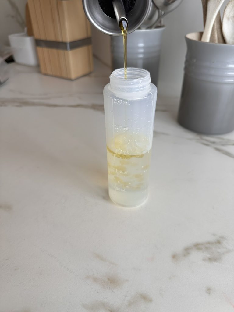 Añadiendo aceite de oliva a un frasco con agua para preparar el agua de Lourdes