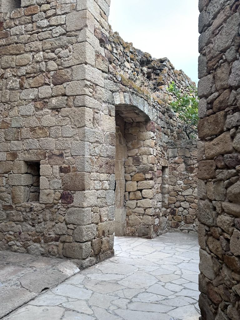Ruinas bien conservadas de la muralla medieval de Pals, construida con piedra y rodeada de vegetación.
