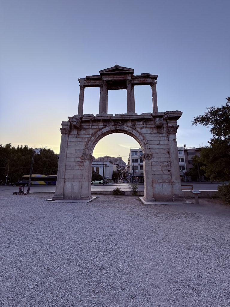 Vista del Templo de Zeus Olímpico en Atenas al atardecer, con columnas iluminadas por la luz dorada y la ciudad al fondo