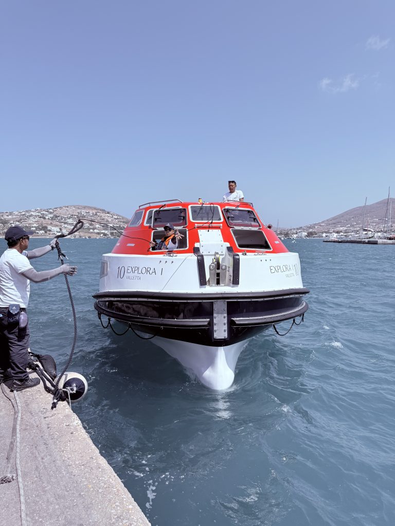 Barca de salvamento roja y blanca transportando pasajeros desde el crucero hasta el puerto de Paros