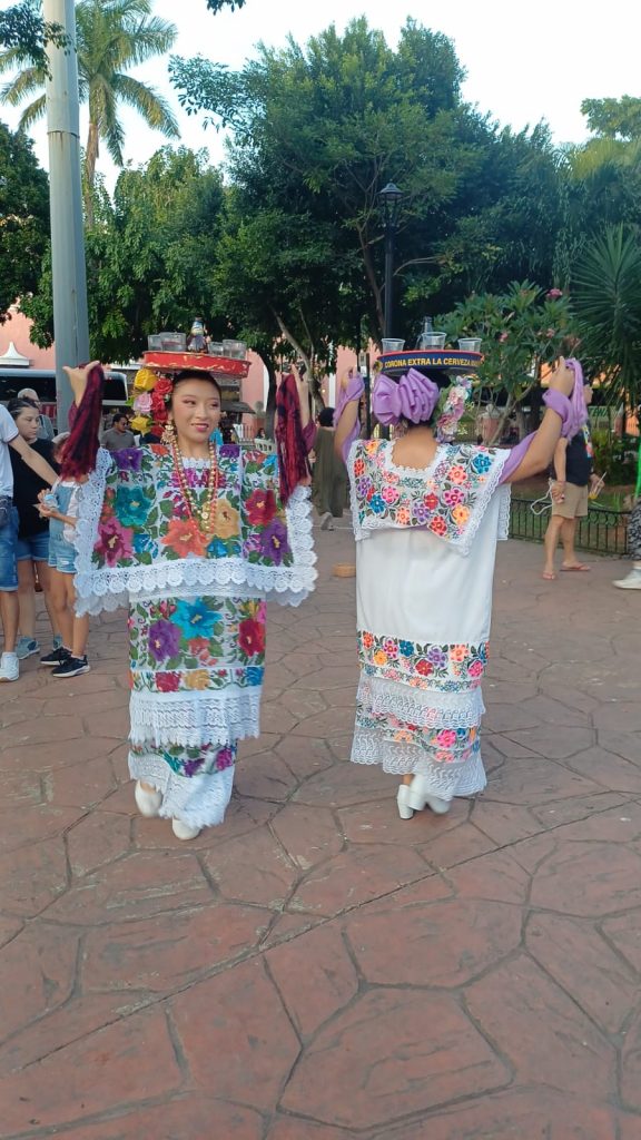 Chicas bailando en Valladolid con trajes regionales yucatecos y bandejas con bebidas equilibradas en la cabeza