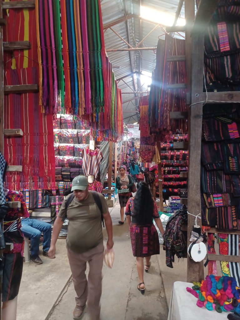 Puestos del mercado de Chichicastenango con textiles mayas y artesanía local.
